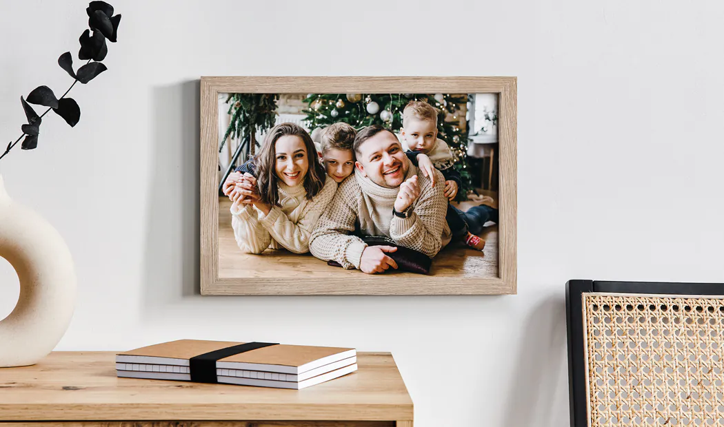 Framed Photo Prints by Printerpix|Personalised family Christmas framed print: happy family of four by the tree.  Warm, festive feel.|Personalised family photos in various sizes, from small to extra-large, beautifully framed.  Create your perfect gallery wall!|Personalised photo print in a high-quality wooden frame, with easel stand or hanging option.  Premium paper & high-definition print.|Personalised family photo: three generations smiling together in a light, airy home. Cherish your memories!|Personalised family photo wall display: cherished moments in stylish white & dark frames, showcasing winter fun & family love.|Personalised photo frames:  Couple's portraits in various styles, creating a loving home display.||||